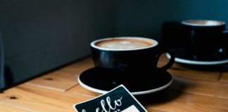 Name sticker and a cup of coffee on a wooden table