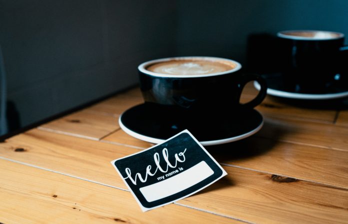 Name sticker and a cup of coffee on a wooden table