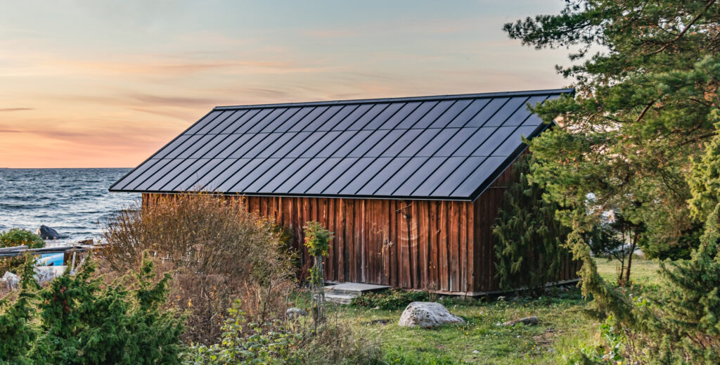 a rustic wooden boat house with a sleek solar roof, set against a scenic background of an ocean and sunset