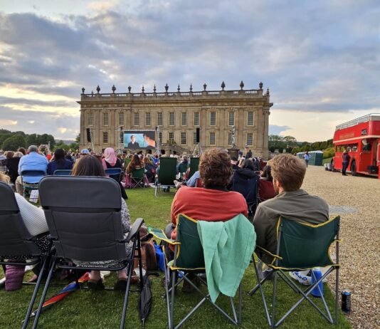 Audience sitting on picnic blankets at an outdoor cinema event at Chatsworth House.