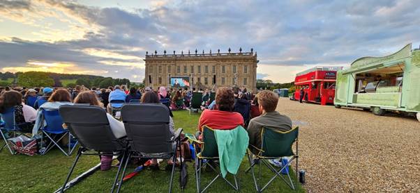 Audience sitting on picnic blankets at an outdoor cinema event at Chatsworth House.